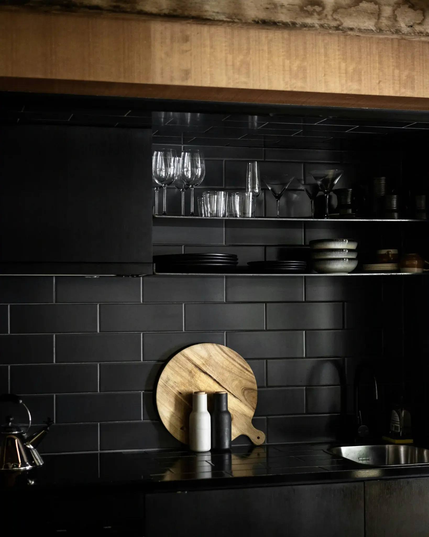 Matte black subway tile backsplash in a dark moody kitchen with open shelving