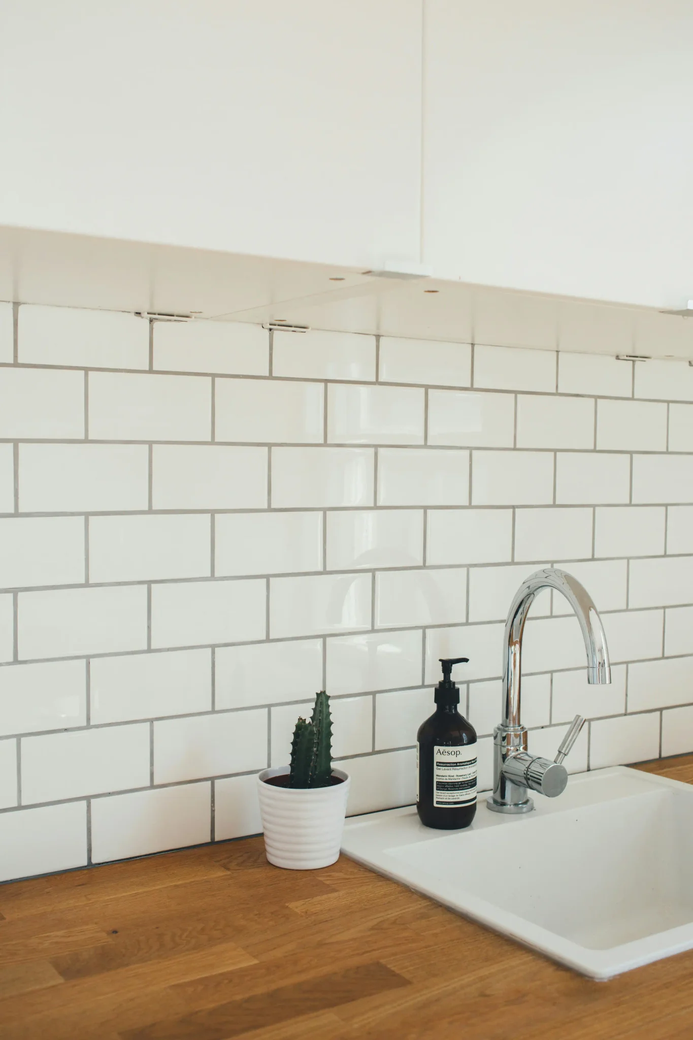 Warm copper-toned square tile backsplash with under-cabinet lighting and black glass upper cabinets