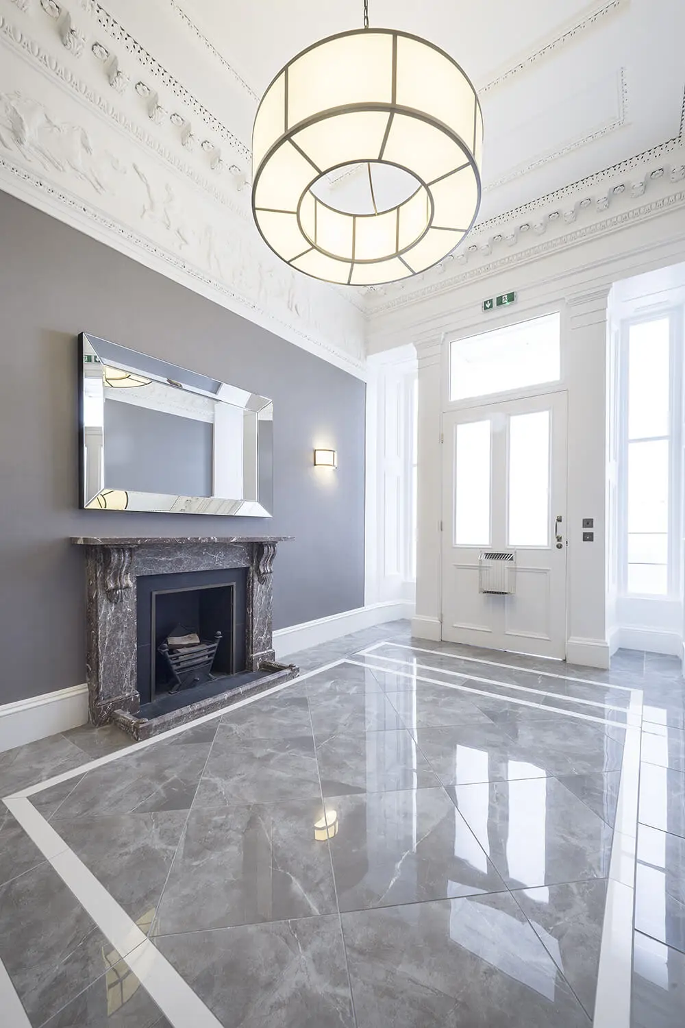 Elegant foyer with large polished gray marble floor tiles, fireplace, and ornate ceiling