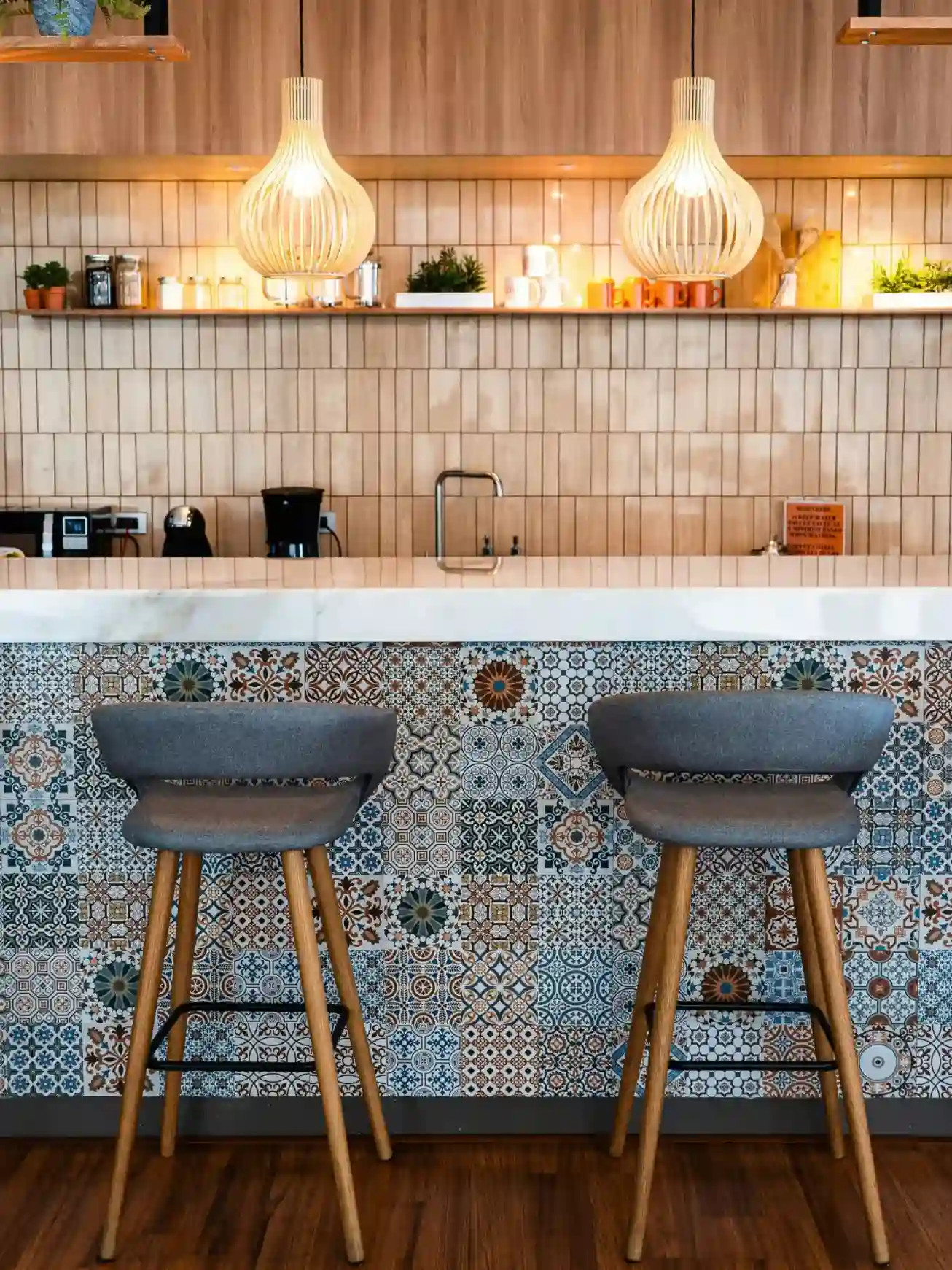 Kitchen island clad in colorful Moroccan patchwork cement tiles with bar stools
