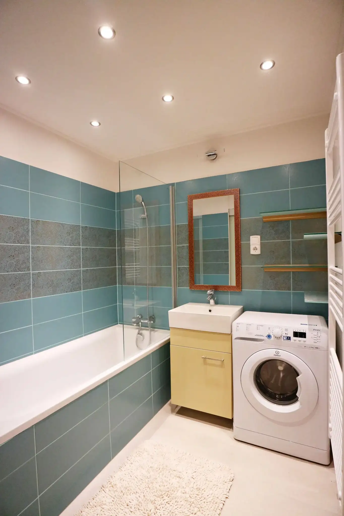 Bathroom with teal rectangular wall tiles, built-in bathtub, and washing machine